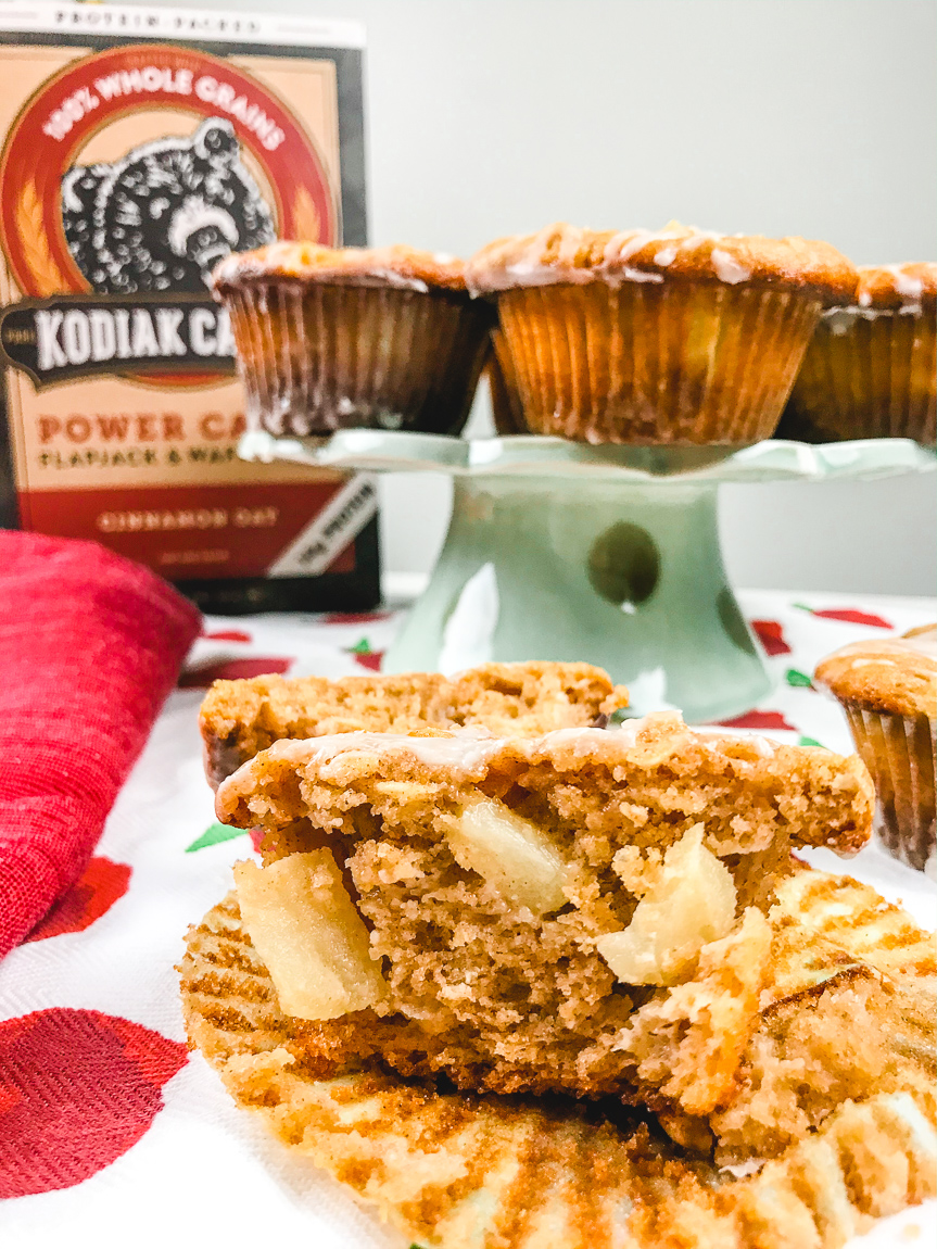 An apple cinnamon muffin cut in half to show the inside of the muffin and apples poking out.