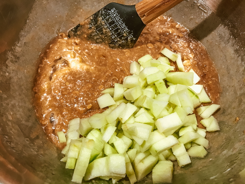 A bowl of muffin mix with chopped apples on top.