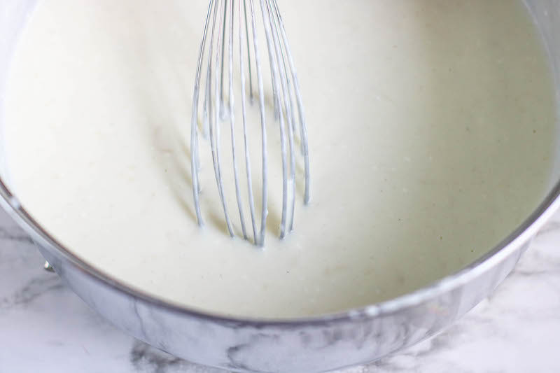 A whisk dipped into a thickened sauce.