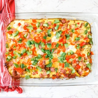 An overhead shot of a breakfast casserole topped with red and green bell peppers.