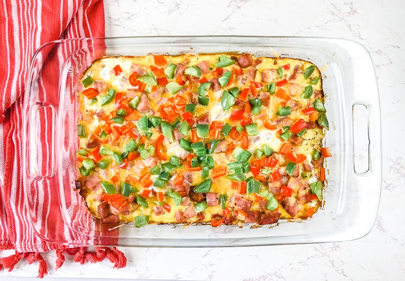 An overhead shot of a breakfast casserole topped with red and green bell peppers.