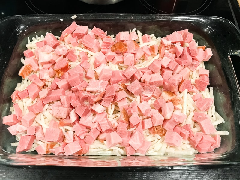 Ham on top of hash browns in casserole dish.