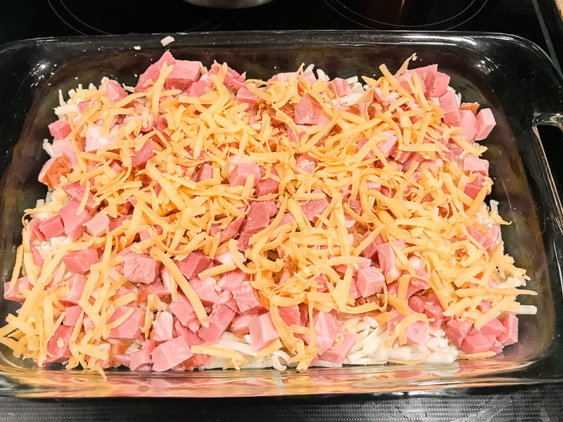 Ham topped with cheese in large glass casserole.