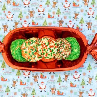 A red cookie shaped dish filled with christmas cookies.