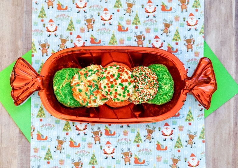 A red cookie shaped dish filled with christmas cookies.