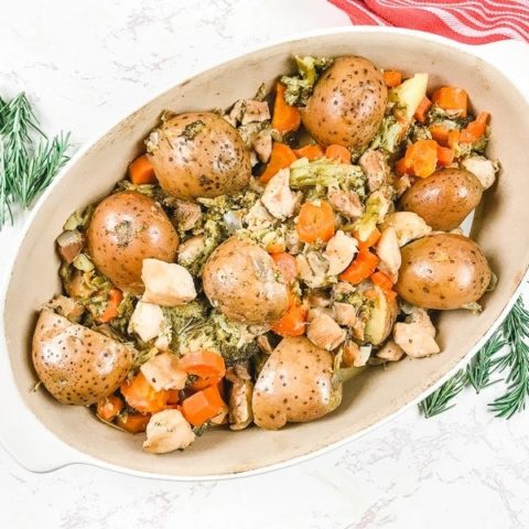 An oval dish filled with chicken, potatoes, carrots, and broccoli.