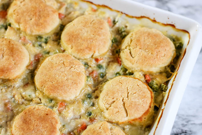 A white baking dish filled with chicken pot pie topped with biscuits.