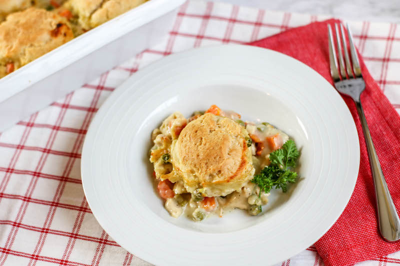 A white plate filled with chicken pot pie and biscuits.