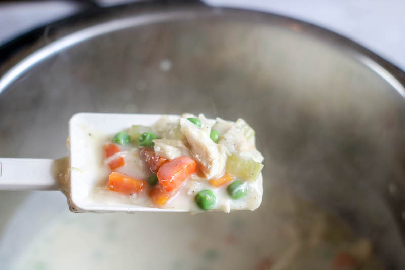 A spoonful of pot pie filling held above instant pot.