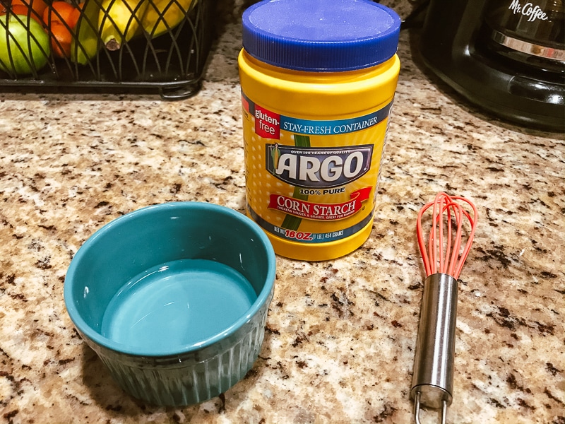 Small blue bowl, small whisk, and container of cornstarch.