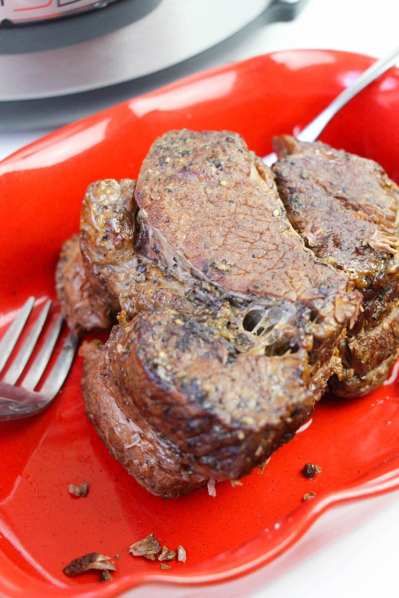 Chuck roast on a red plate next to two forks.