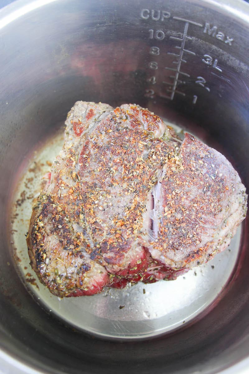 Chuck roast being seared in a pot.