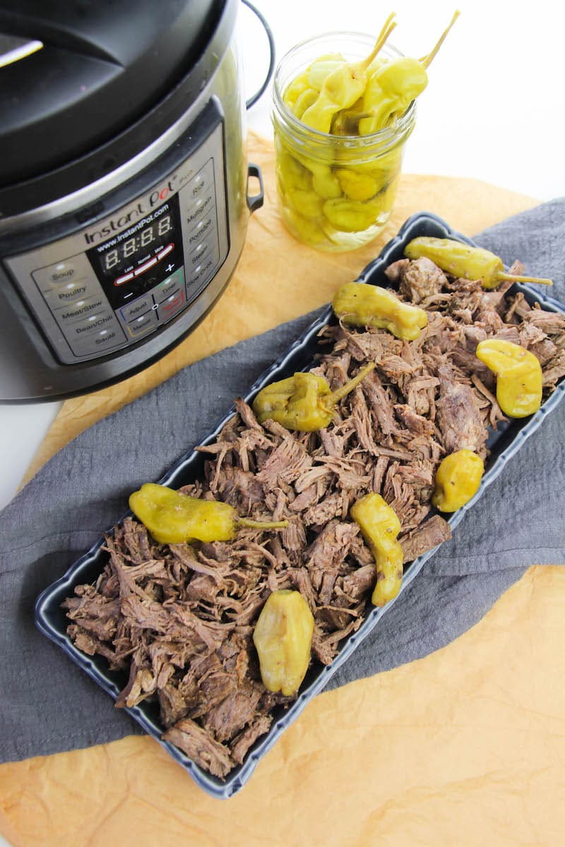 Instant pot, plate of Italian beef, and jar of peppers.