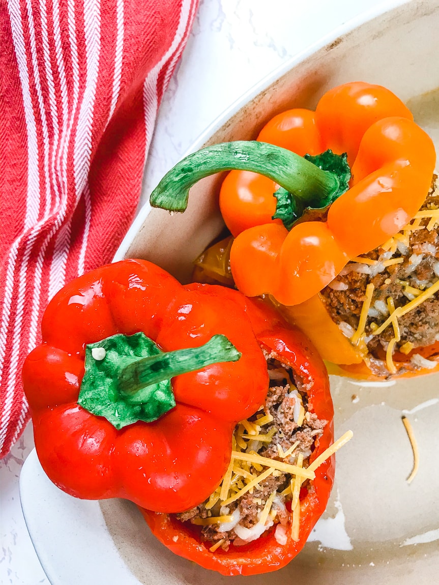 A red and orange stuffed pepper next to each other in a serving dish.