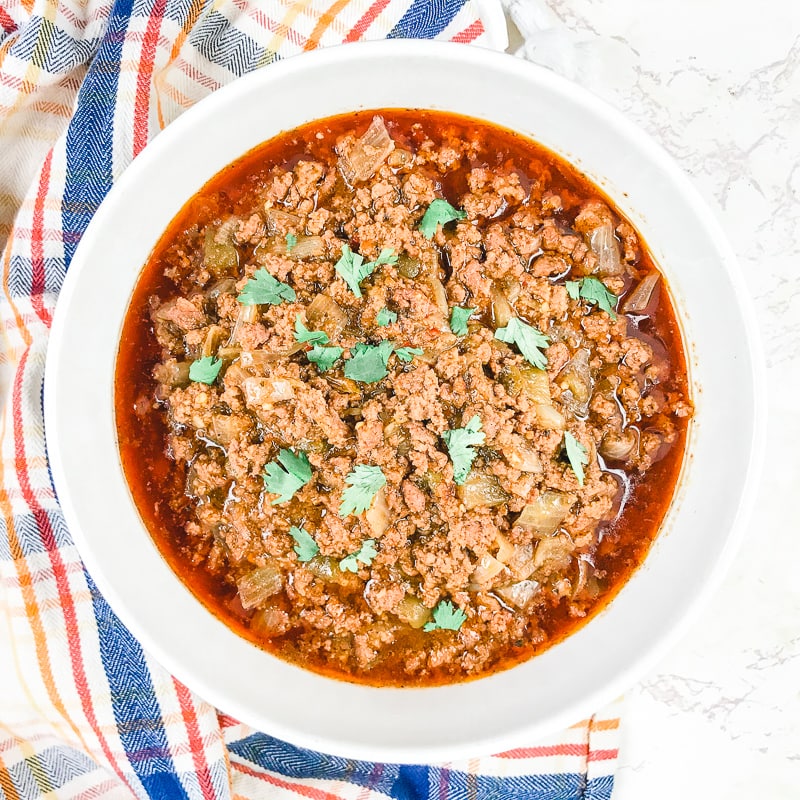 A bowl of instant pot taco meat next to a blue and red plaid towel.