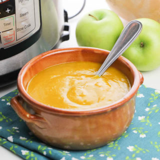 butternut squash soup in a red ceramic bowl in front of instant pot.