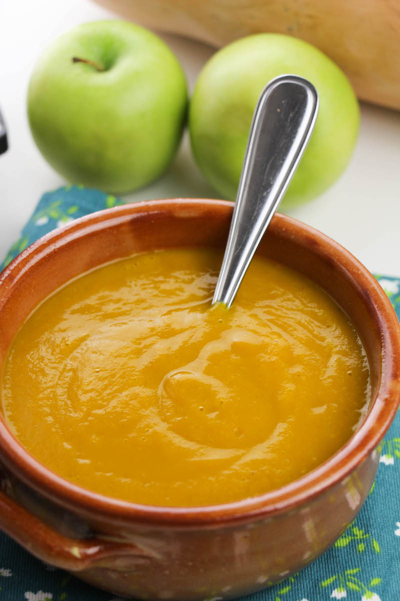A bowl of butternut squash soup with a spoon sticking out.