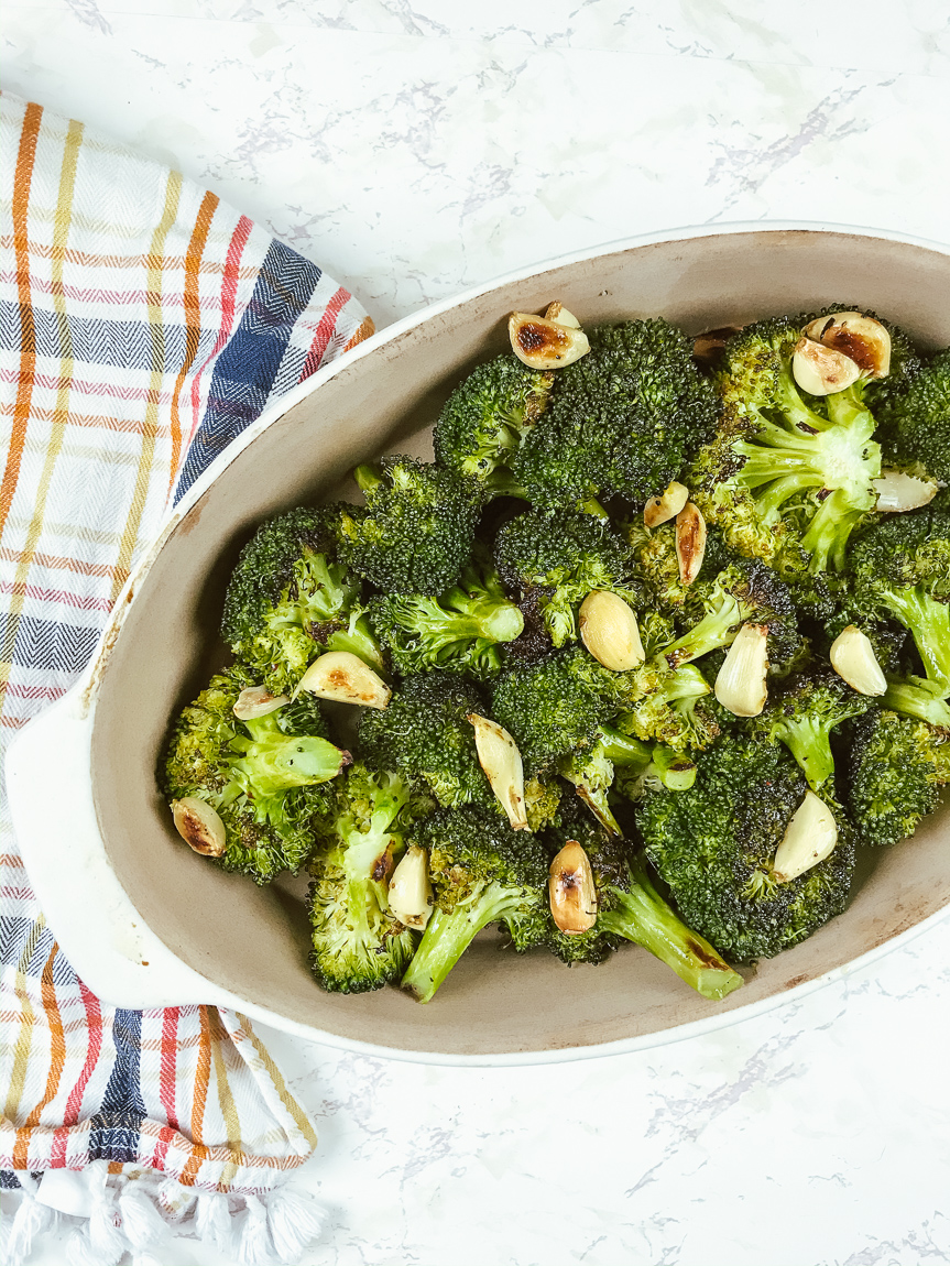 Oval shaped casserole dish filled with roasted broccoli.