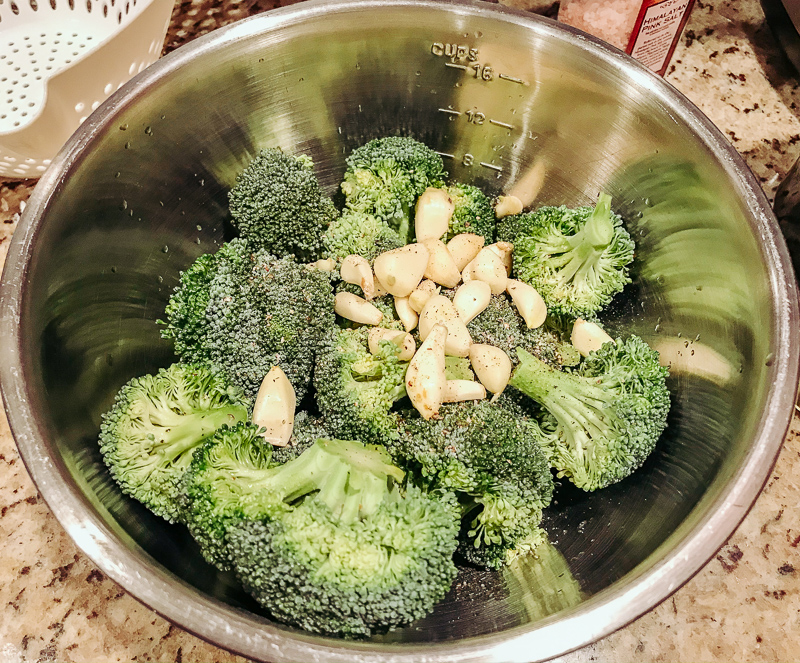 Garlic and broccoli in a metal bowl.