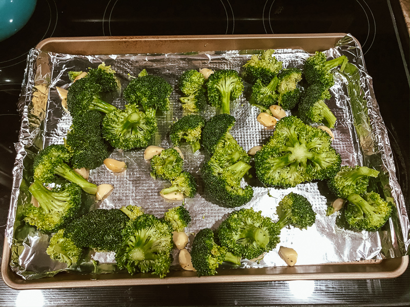 Broccoli and garlic on a foil-lined cookie sheet.