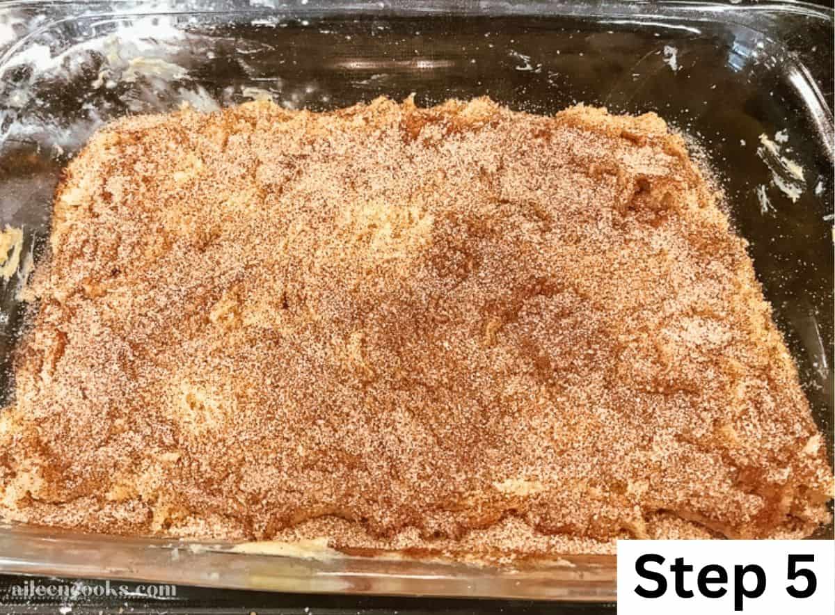 Two layers of cookie dough bar dough spread out in a glass baking dish and topped with cinnamon sugar.