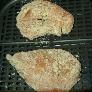 Parmesan coated chicken inside air fryer.