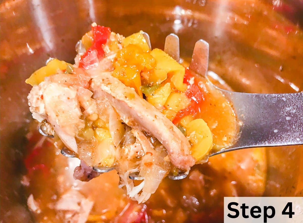 A ladle full of cooked chicken fajitas over a large silver pot.