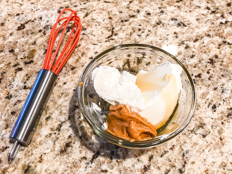 A small glass bowl with yogurt, honey, and peanut butter.