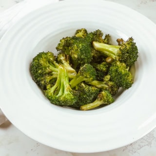 Air fryied broccoli in white rimmed bowl.