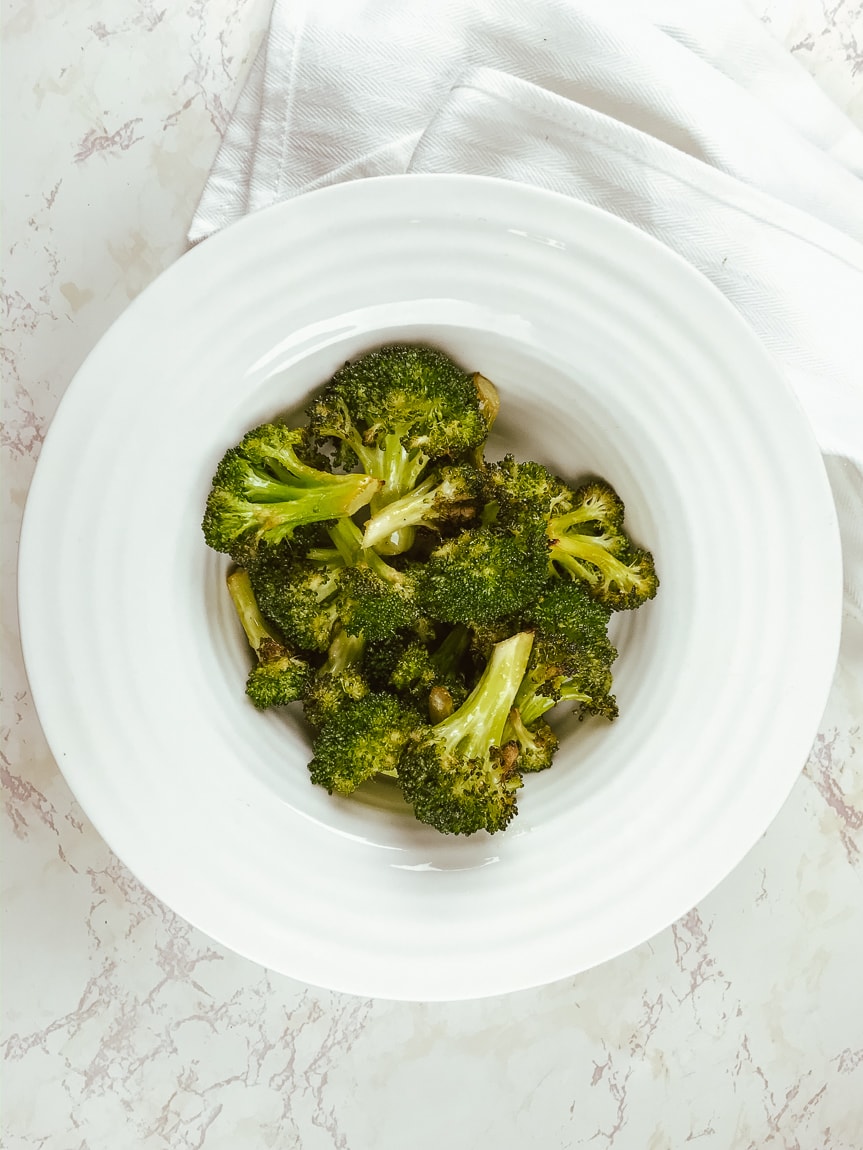 A white rimmed bowl filled with air fried broccoli.