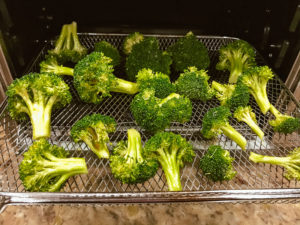 Raw broccoli on tray in air fryer oven.