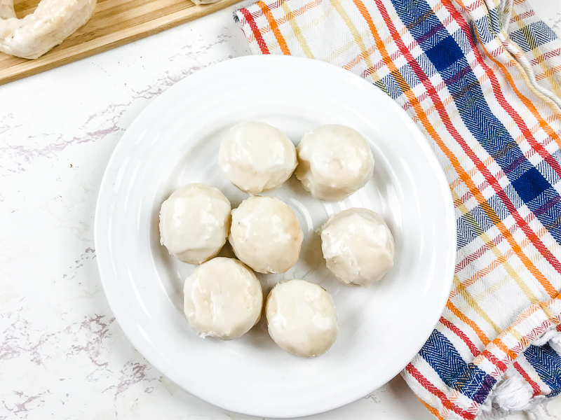 A white plate filled with glazed donut holes.