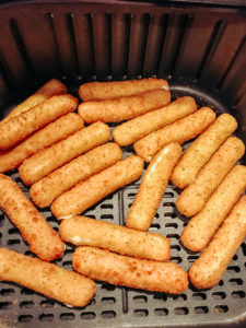 Breaded mozzeralla sticks inside air fryer.