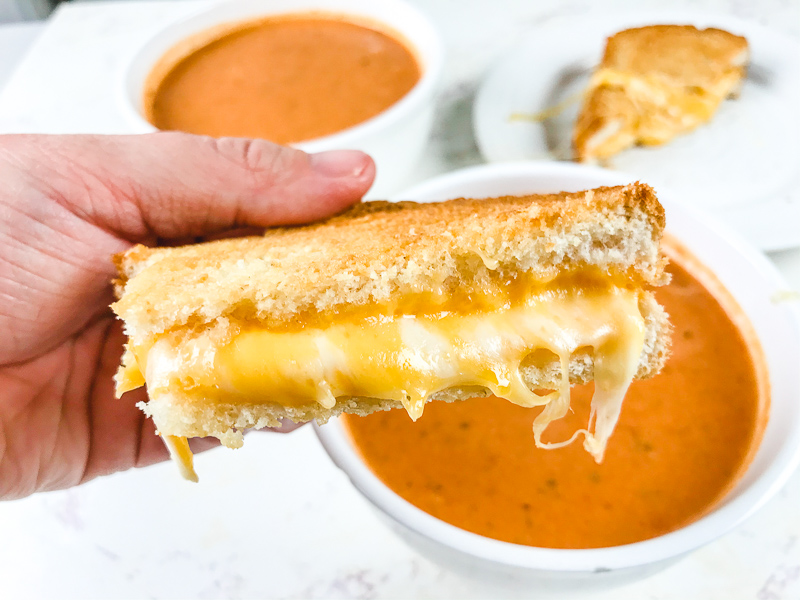 A hand holding up half of a grilled cheese.