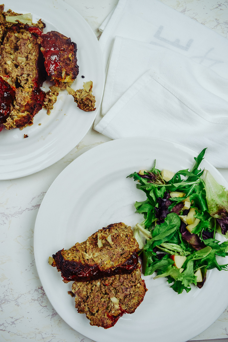 White plate with two slices of meatloaf and a green salad.