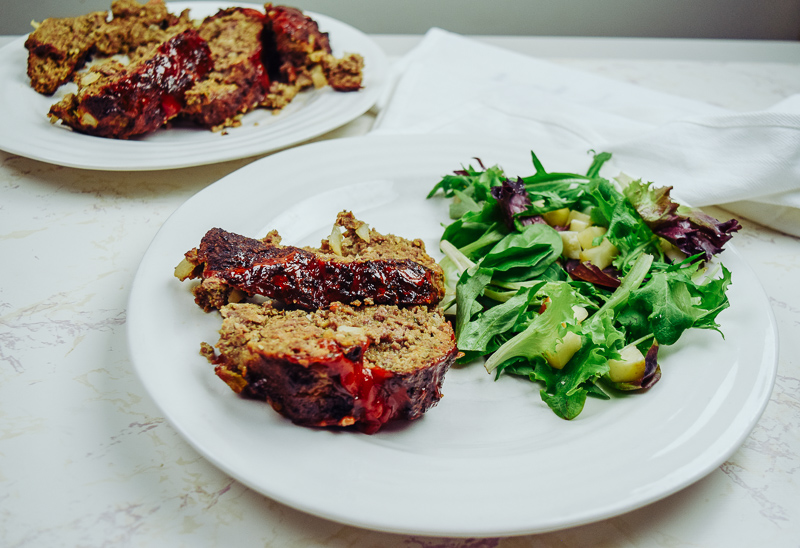 Plate of meatloaf and salad in front of platter of air fried meatloaf.