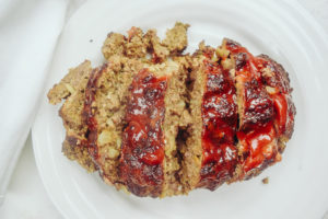 Sliced meatloaf topped with ketchup on a white plate.
