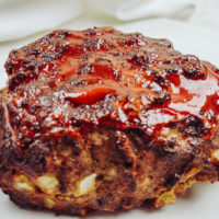 Side view of cooked meatloaf slathered in ketchup.