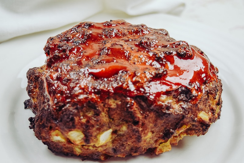 Side view of cooked meatloaf slathered in ketchup.