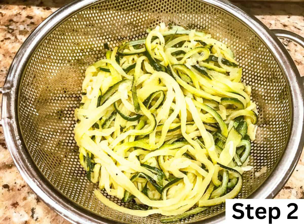 Cooked zucchini noodles draining in a mesh sieve.
