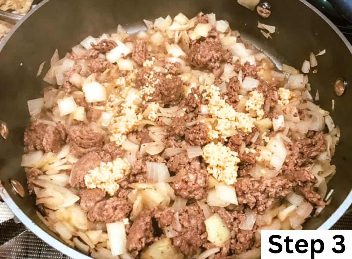 Ground beef, diced onion, and minced garlic cooking in a pan.