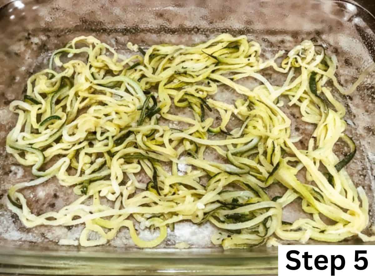 Zucchini noodles spread out in a glass baking dish.
