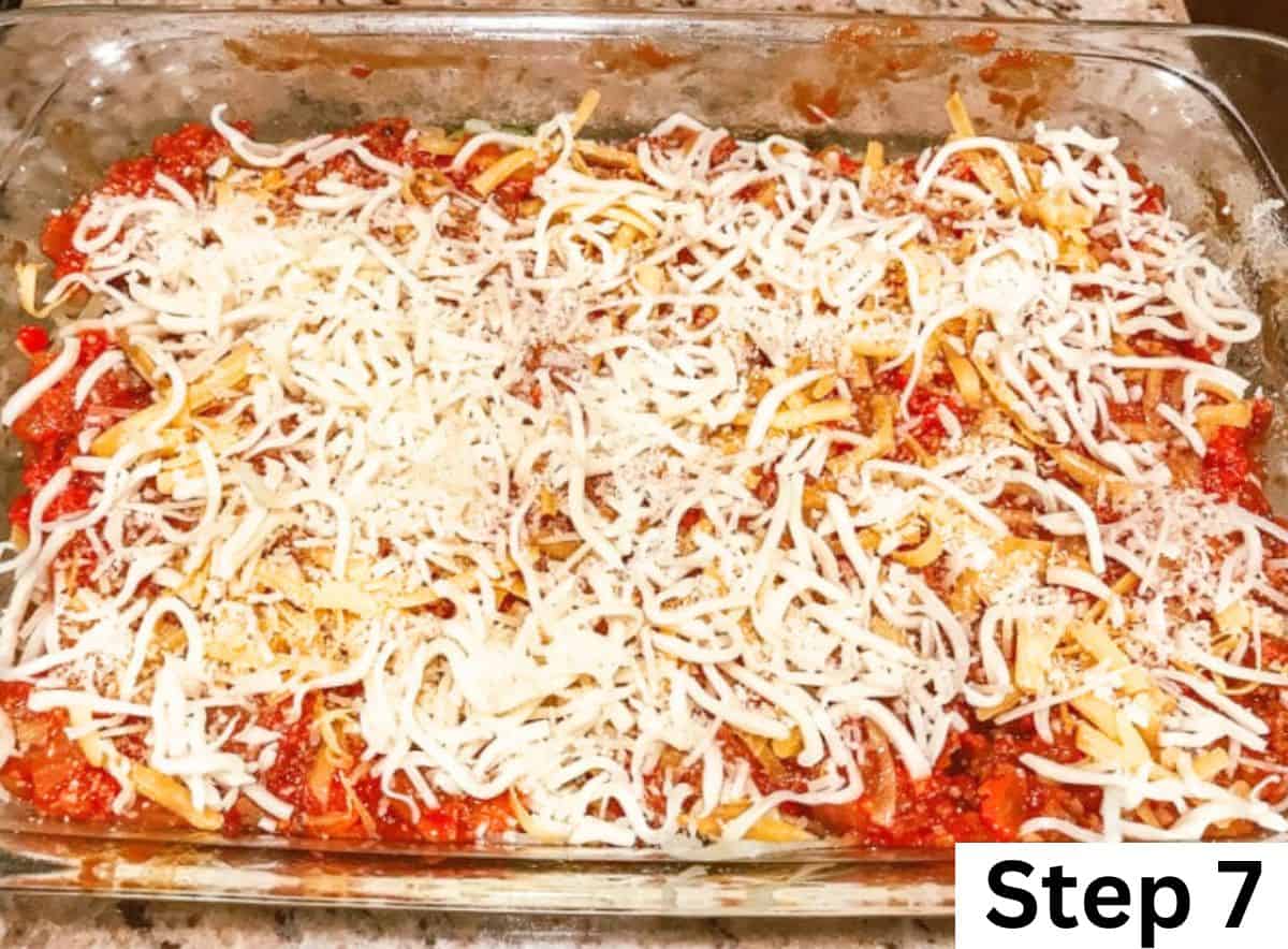 A glass baking dish filled with zucchini noodles, spaghetti sauce, and cheese. 
