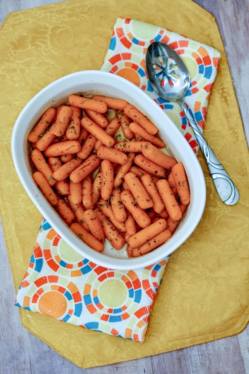 A baking dish filled with buttered carrots on top of a yellow placemat.