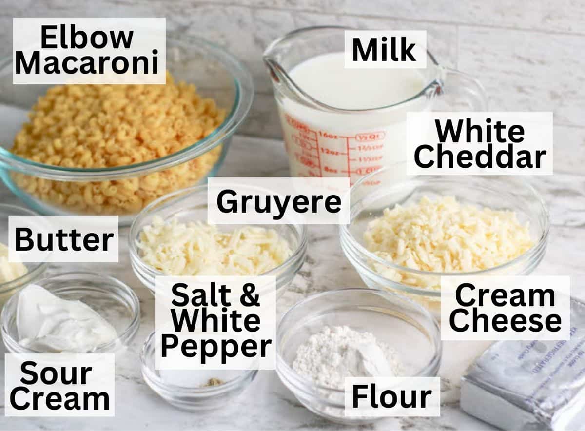 Ingredients for homemade mac and cheese in glass bowls on a white counter.