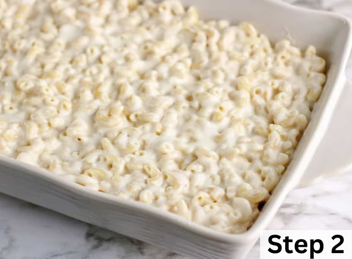A white casserole dish filled with elbow macaroni coated in a creamy cheese sauce.