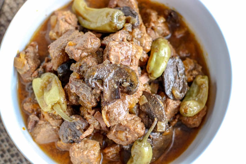 Crockpot beef tips with gravy and mushrooms in white bowl.