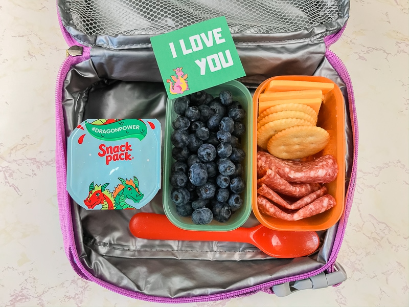 Lunchbox with salami, cheese, blueberries, snack pack, and lunch note that says "I love you".