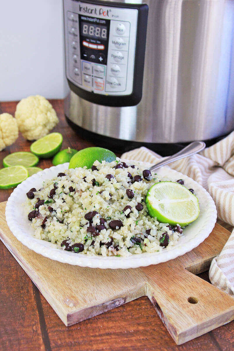 A white plate of cilantro lime cauliflower rice in front of an instant pot.