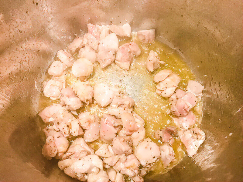 Cubed chicken cooking inside instant pot.